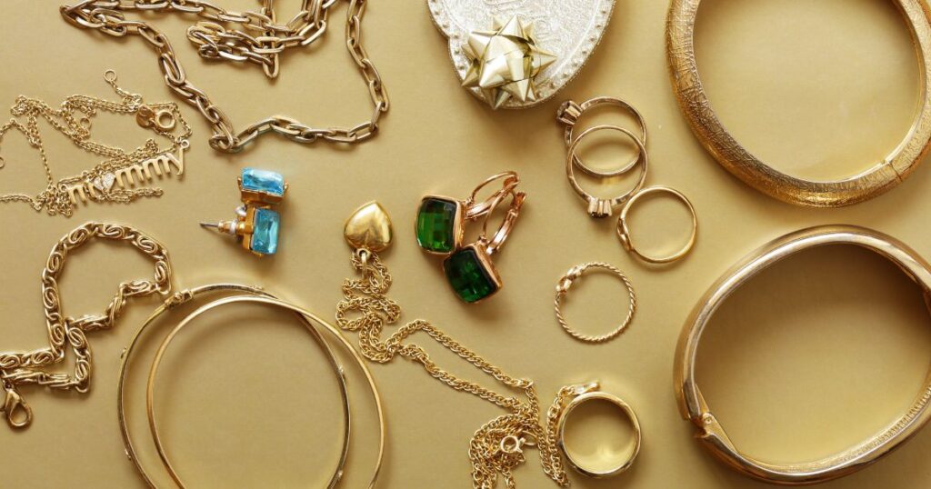 Gold jewelry on a table: rings, bracelets, and necklaces in various styles and designs.